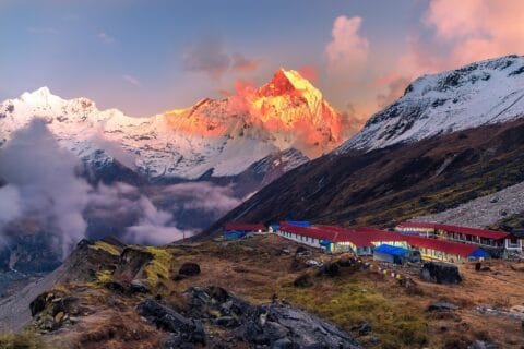 Snowy Himalayan peaks glow at sunrise near Annapurna Base Camp.