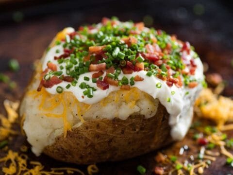 Loaded baked potato topped with sour cream, cheese, bacon, and chives.