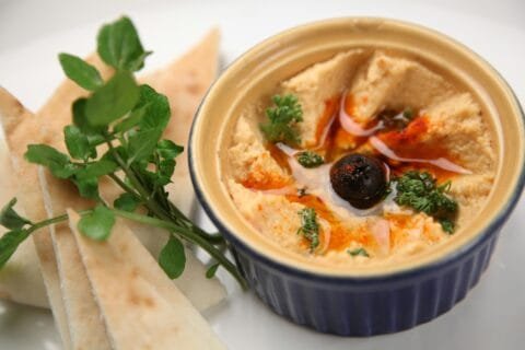 Hummus with herbs and olive served with pita bread