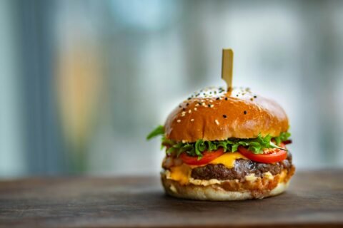 Close-up of a gourmet cheeseburger with lettuce and tomato on a wooden surface