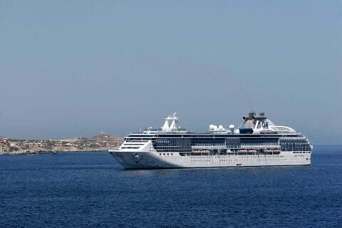 Luxurious white cruise ship sailing near coastal destination