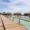 Scenic view of Palafitos Overwater Bungalows in Mexico with thatched roofs, clear turquoise water, and a wooden walkway leading over the ocean under a sunny sky.