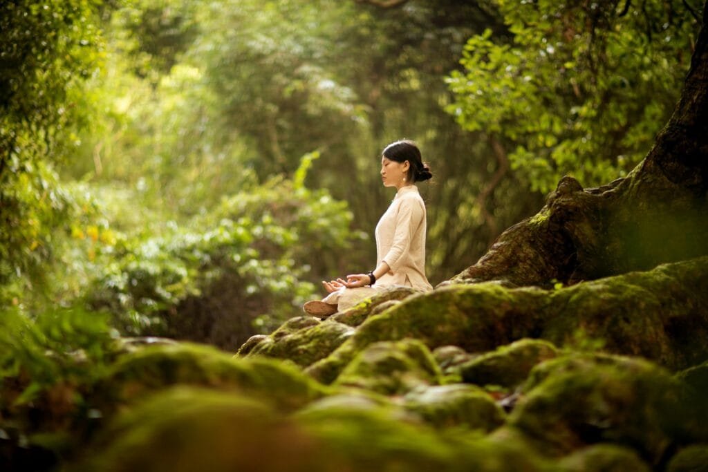 Woman meditating in forest during yoga retreat in Bali