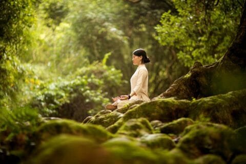 Woman meditating in forest during yoga retreat in Bali