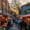 Busy Hackney market at sunset with people shopping for fresh produce, vibrant food stalls under red-striped canopies, and colorful graffiti on surrounding buildings.