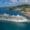 Large Royal Caribbean cruise ship "Jewel of the Seas" docked at a scenic Mediterranean port, surrounded by turquoise waters and a colorful coastal town with lush green hills.