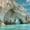 Natural limestone sea arch formations over clear turquoise waters along the coast of Zakynthos, Greece, under a bright blue sky with wispy clouds.