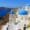 Iconic view of Santorini, Greece, featuring whitewashed buildings with blue-domed churches perched on cliffs overlooking the deep blue Aegean Sea and caldera.