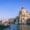 Gondola gliding through the Grand Canal in Venice at sunset, passing by the iconic Basilica di Santa Maria della Salute.