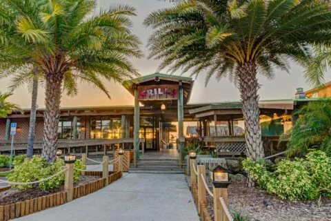 A Foodie’s Guide to the 8 Best Seafood Restaurants in Melbourne Beach Florida 108 Entrance to Grills restaurant with palm trees and tropical landscaping.