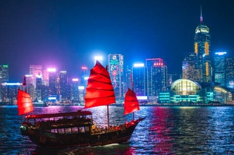 Traditional junk boat sailing across Victoria Harbour at night, Hong Kong Island