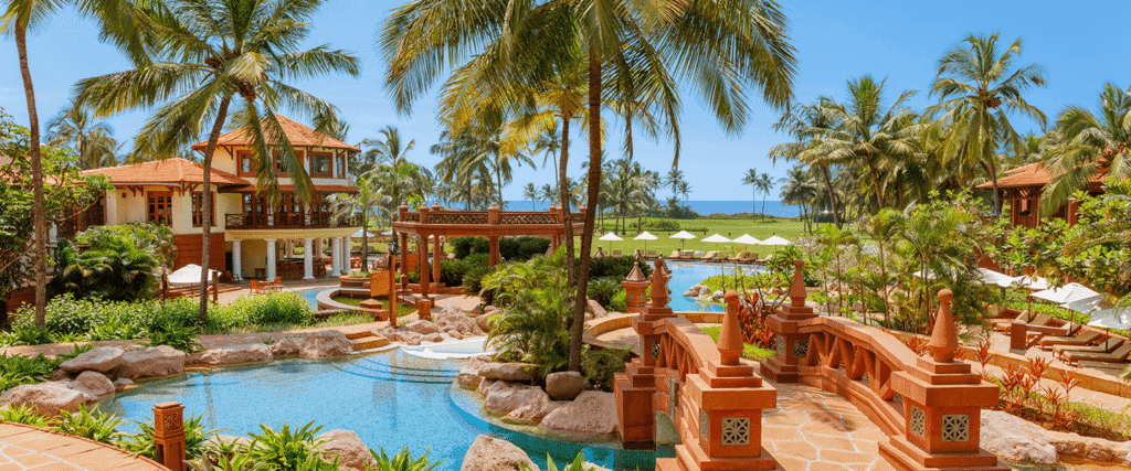 Poolside at ITC Grand Goa Resort & Spa, Arossim with palm-lined gardens and a tropical lagoon setting