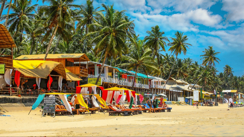 Rustic wooden cottages and palm trees at a beach resort in Goa