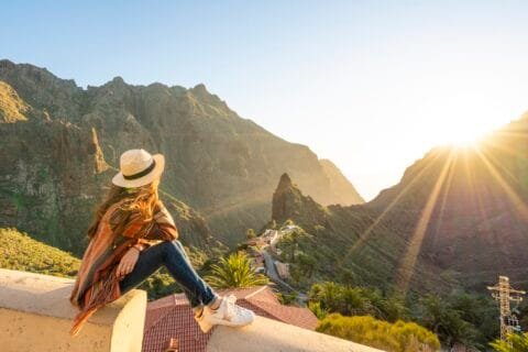 Woman enjoying a mountain valley view at sunset while traveling solo.